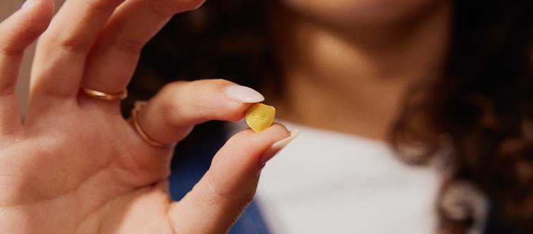 Hände halten eine gelbe Pille in Form eines Schildes